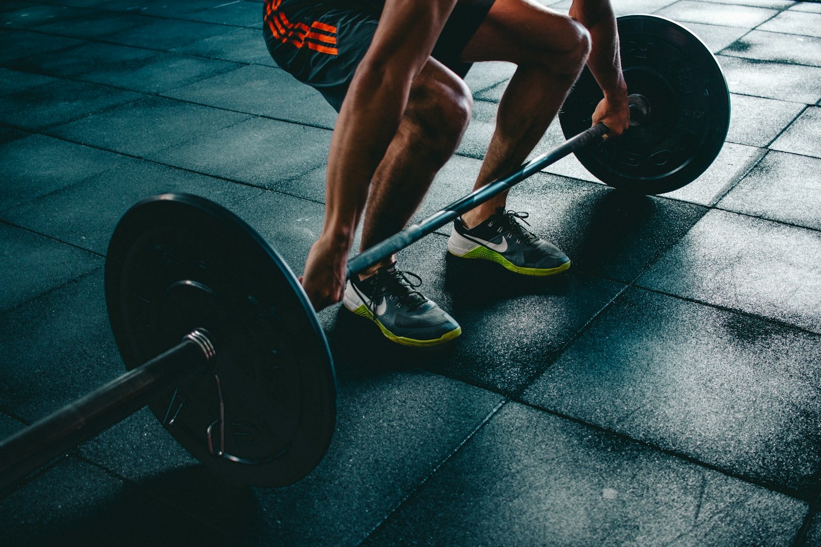 A lifter standing at a loaded barbell in a gym, preparing to pull