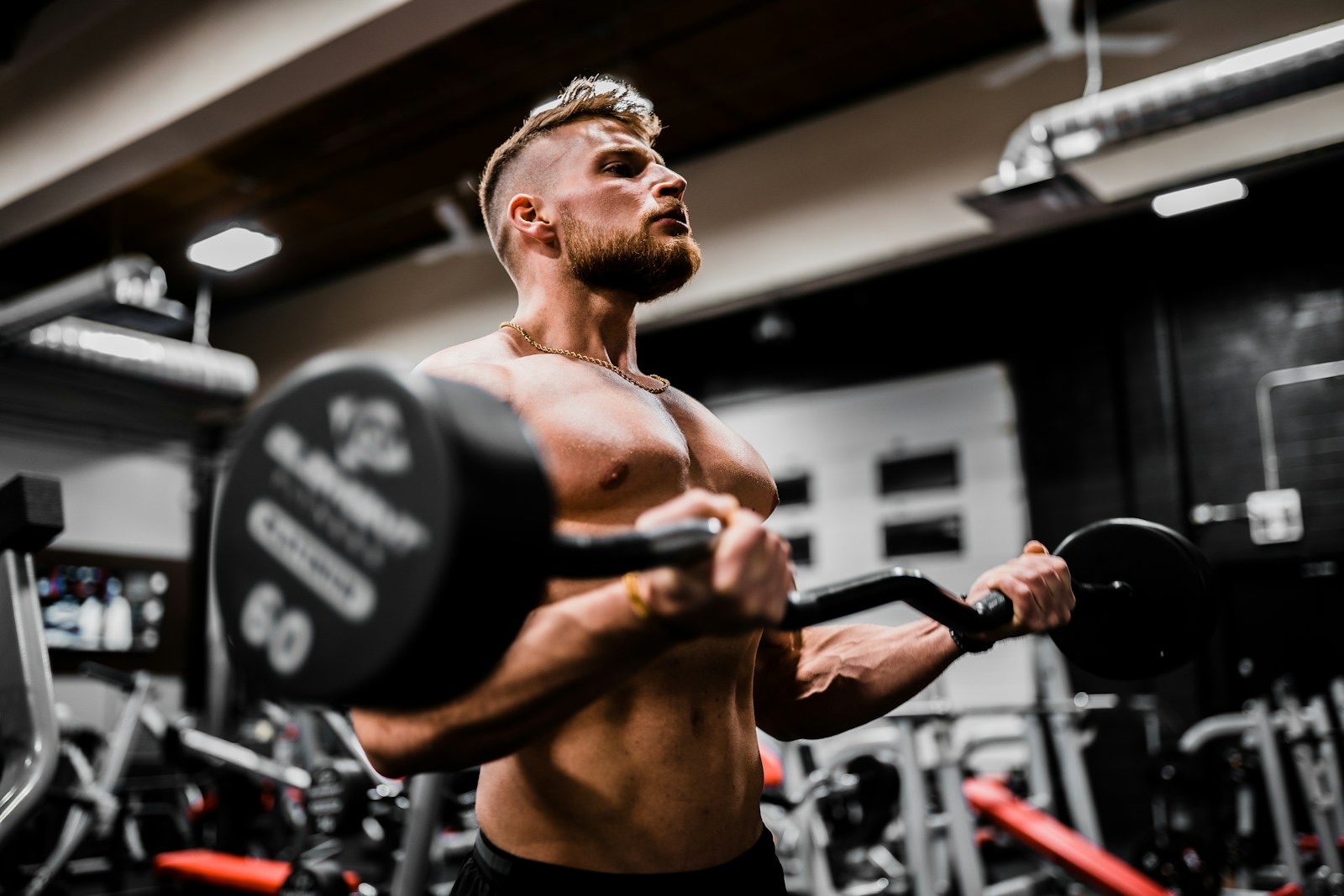 A lifter carrying a single dumbbell across a dark gym