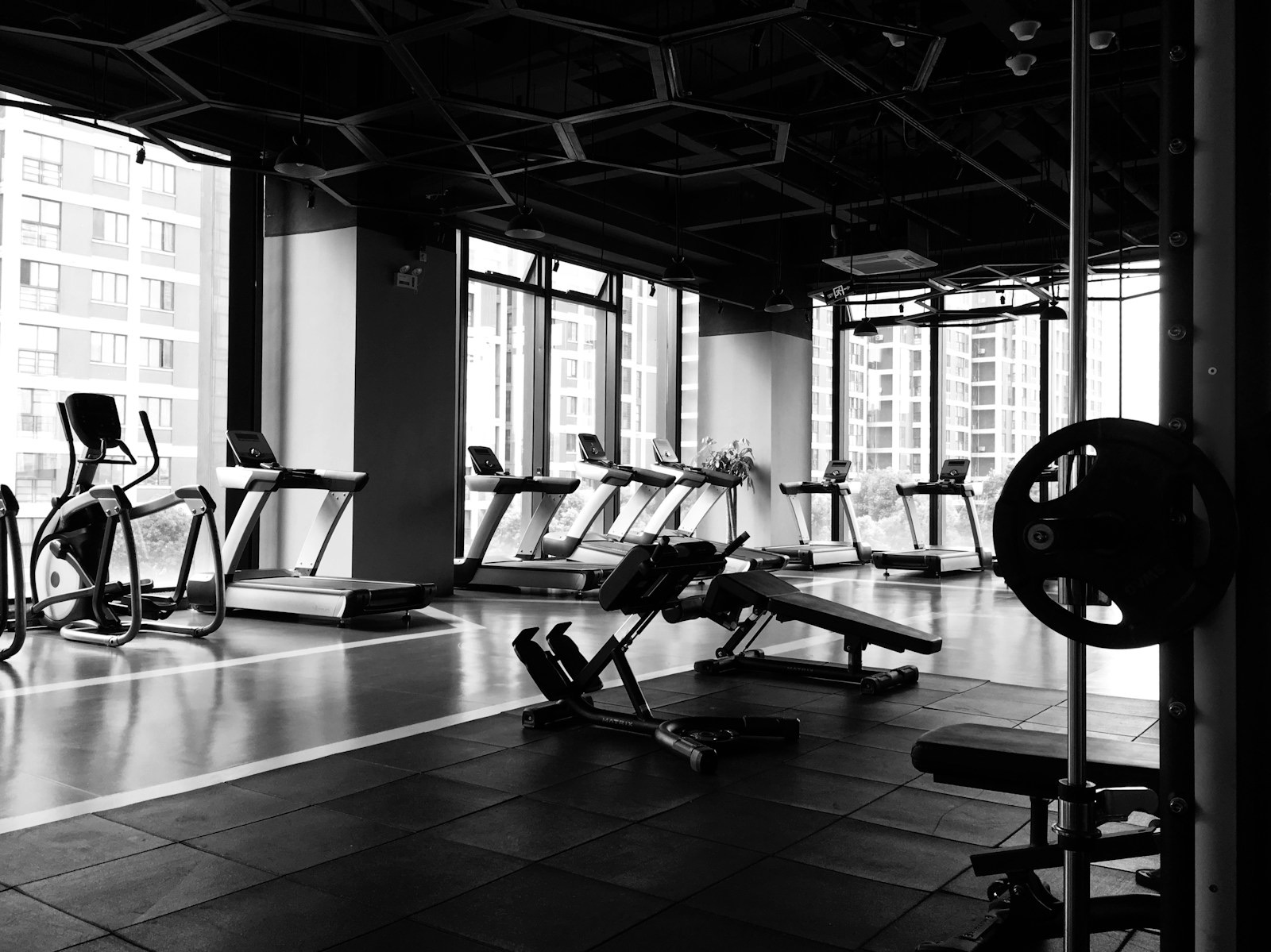 A quiet gym floor with racks and benches in black and white